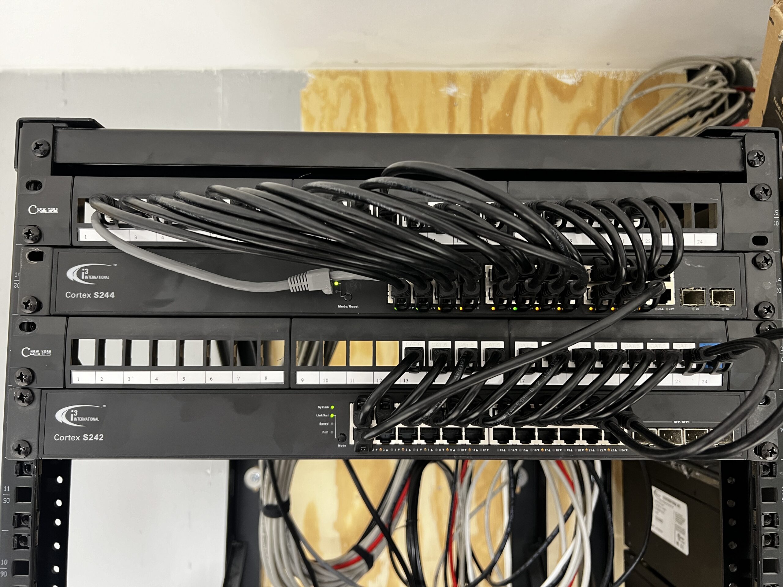 Installed network switches and patch panels with neatly routed black patch cables